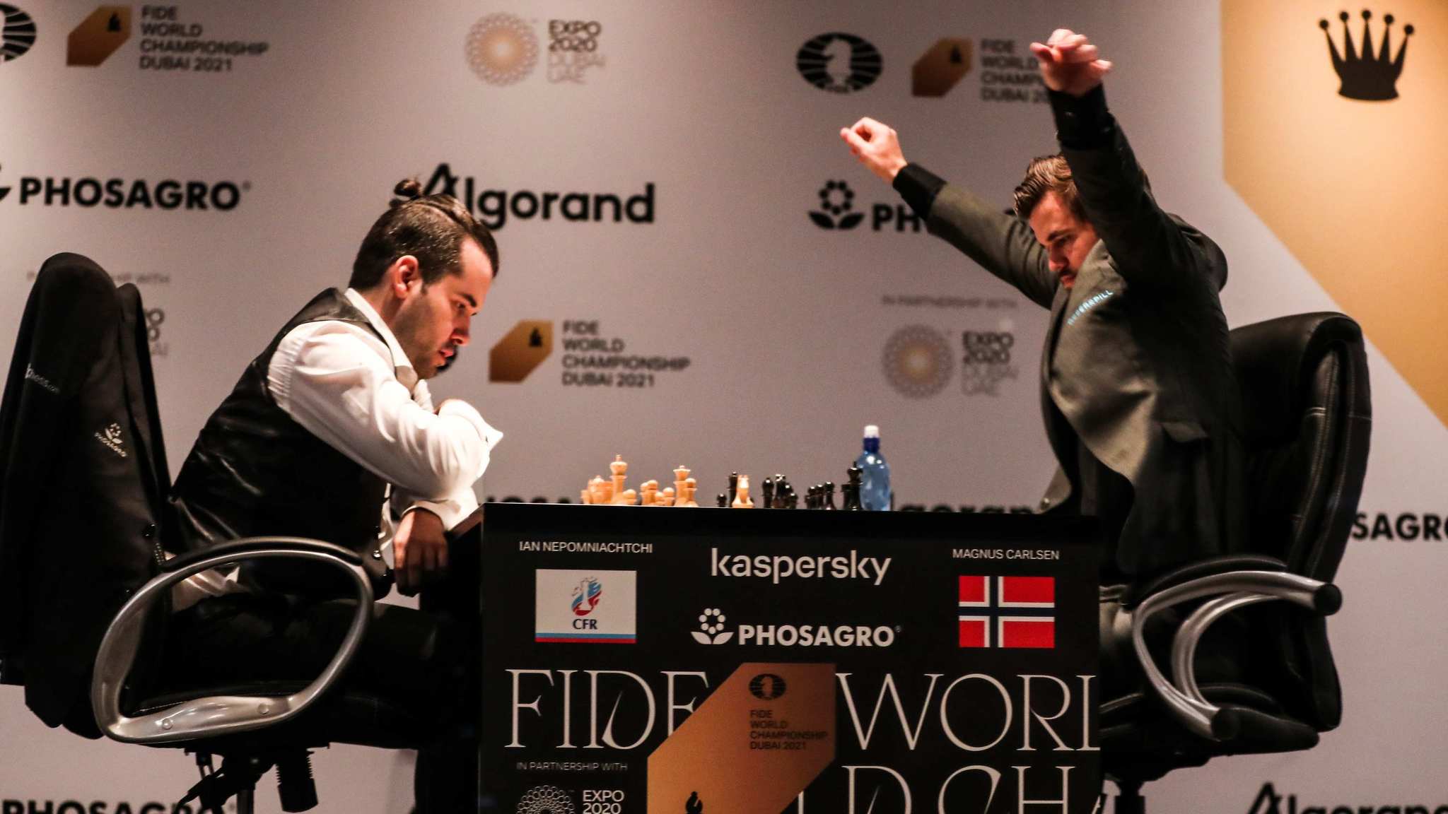 Carlsen, a la derecha, se estira durante la primera partida del Mundial