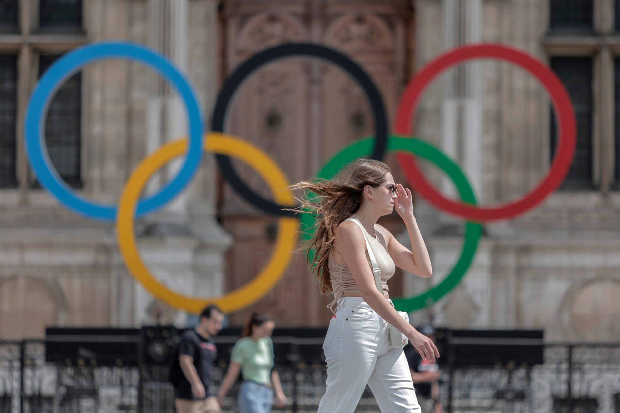 Una parisina camina por París con los aros olímpicos al fondo