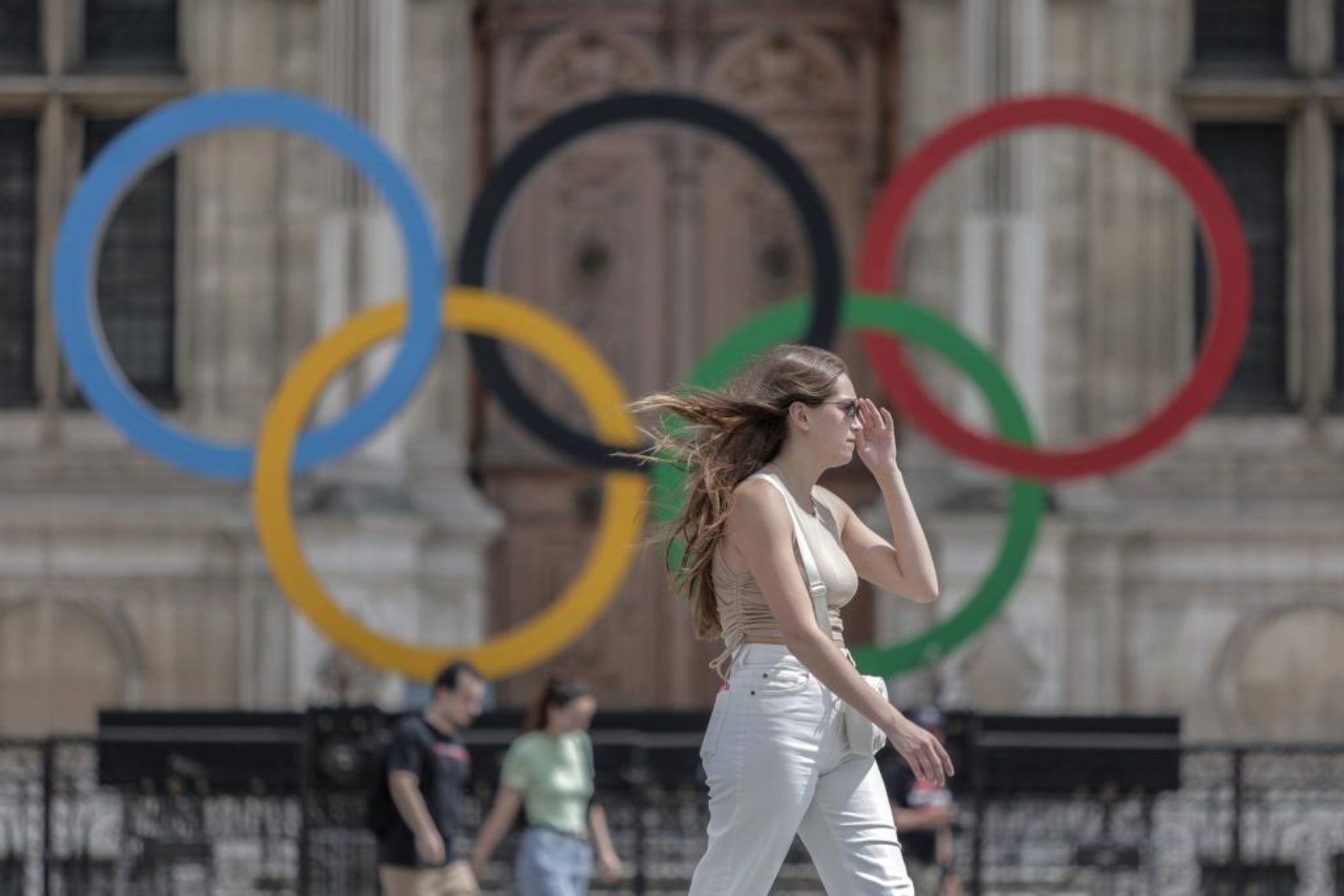 Una mujer pasea delante de los aros olímpicos en París