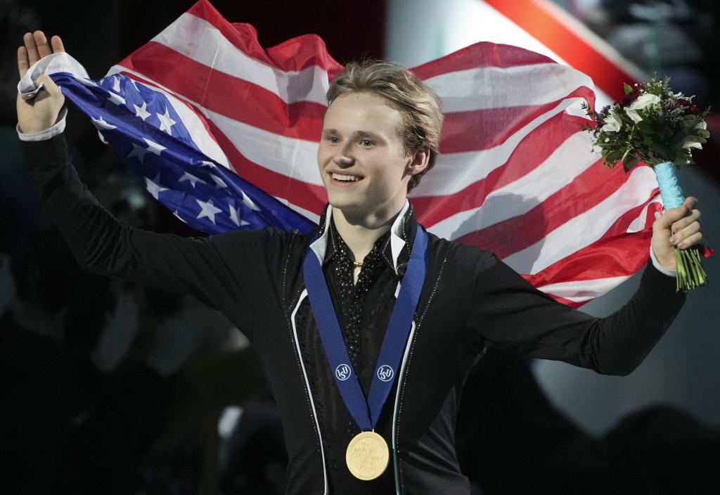 Ilia Malinin festeja su medalla de oro envuelto en la bandera de Estados Unidos