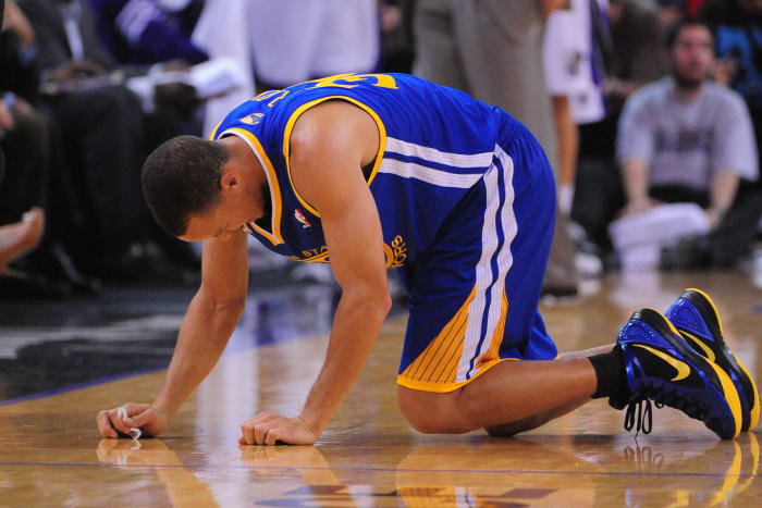 Stephen Curry, agachado en el parquet durante un partido de los Warriors.