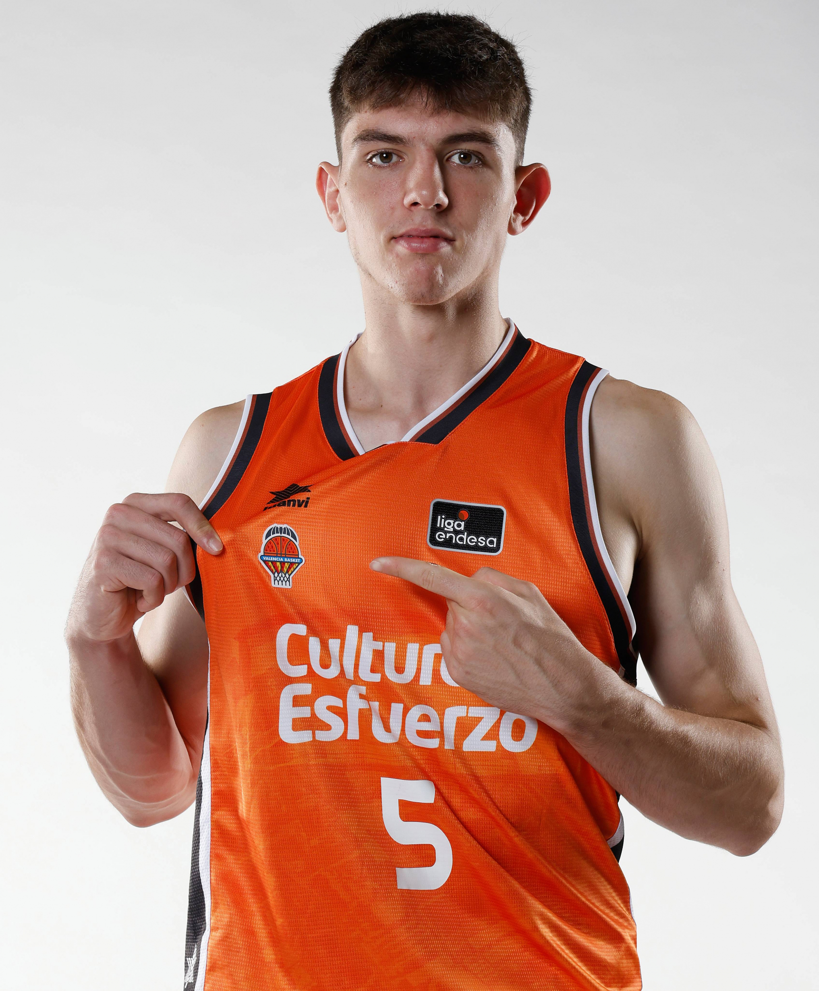 Sergio de Larrea señala el escudo del Valencia Basket en su camiseta.
