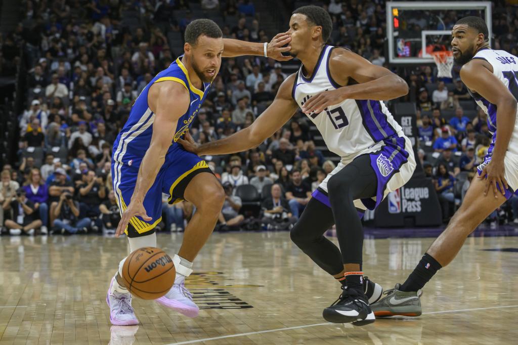 Stephen Curry trata de superar la defensa de Keegan Murray.