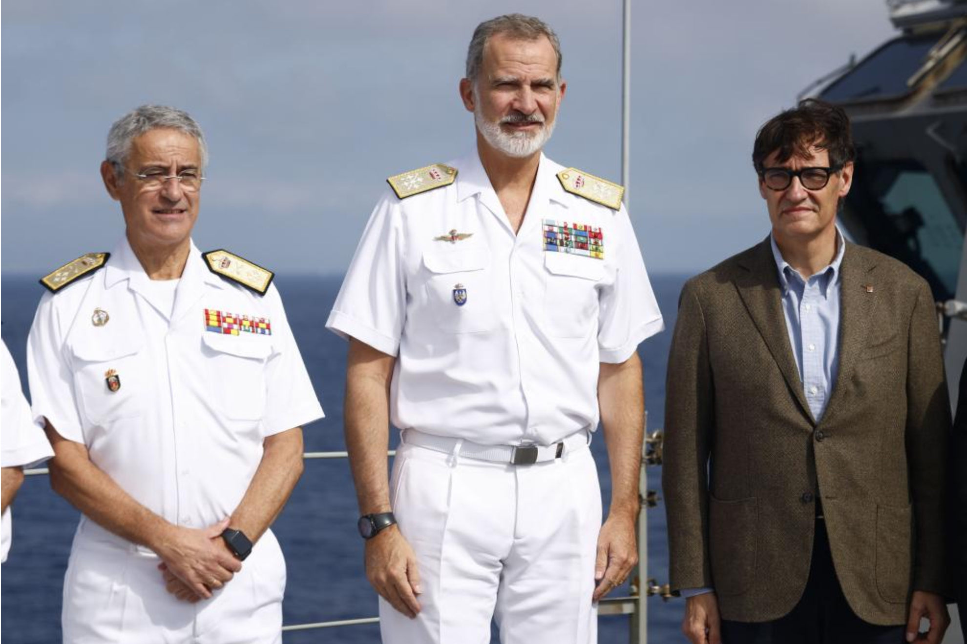 El rey Felipe VI, acompañado del presidente de la Generalitat de Cataluña, Salvador Illa (d, y el Almirante Jefe de Estado Mayor de la Armada (AJEMA), Antonio Piñeiro (i)..