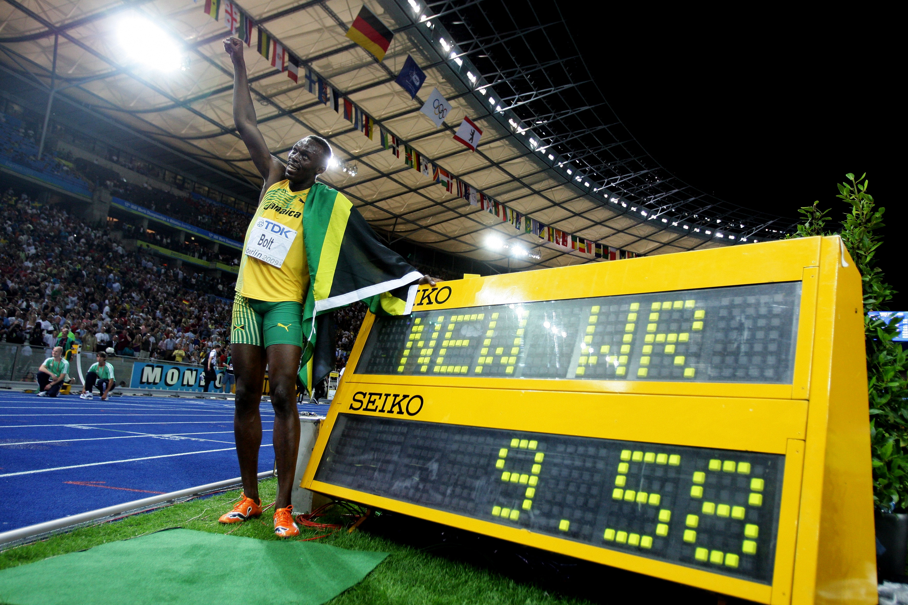 Usain Bolt posa junto a su récord del mundo de los 100 metros en Berlín 2009.