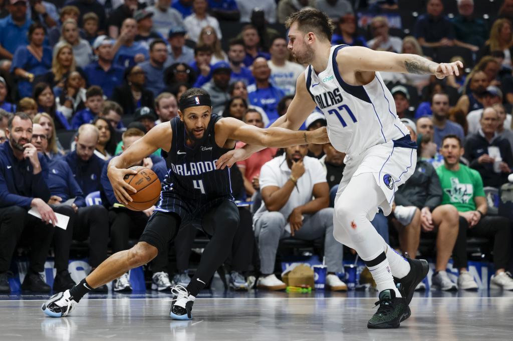 Obrońca Orlando Magic Jalen Suggs (4) wpada do kosza, broniony przez obrońcę Dallas Mavericks Lukę Doncica (77) podczas drugiej połowy meczu koszykówki NBA, niedziela, 3 listopada 2024 r. w Dallas. (AP Photo/Gareth Patterson)