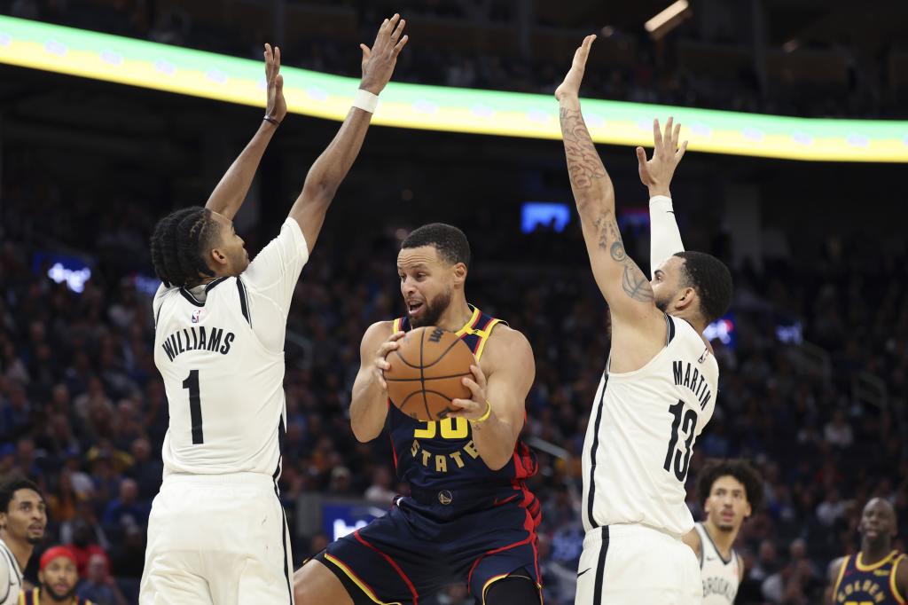 Golden State Warriors guard Stephen Curry (30) is guarded by Brooklyn Nets forward Ziaire Williams (1) and guard Tyrese Martin (13) during the second half of an NBA basketball game in San Francisco, Monday, Nov. 25, 2024. (AP) Photo/Jed Jacobsohn)