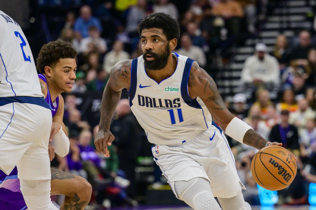 O armador do Dallas Mavericks, Kyrie Irving (11), dribla o zagueiro Keyonte George (centro), do Utah Jazz, durante o primeiro tempo de um jogo de basquete da NBA no sábado, 30 de novembro de 2024, em Salt Lake City. (Foto AP/Tyler Tate)