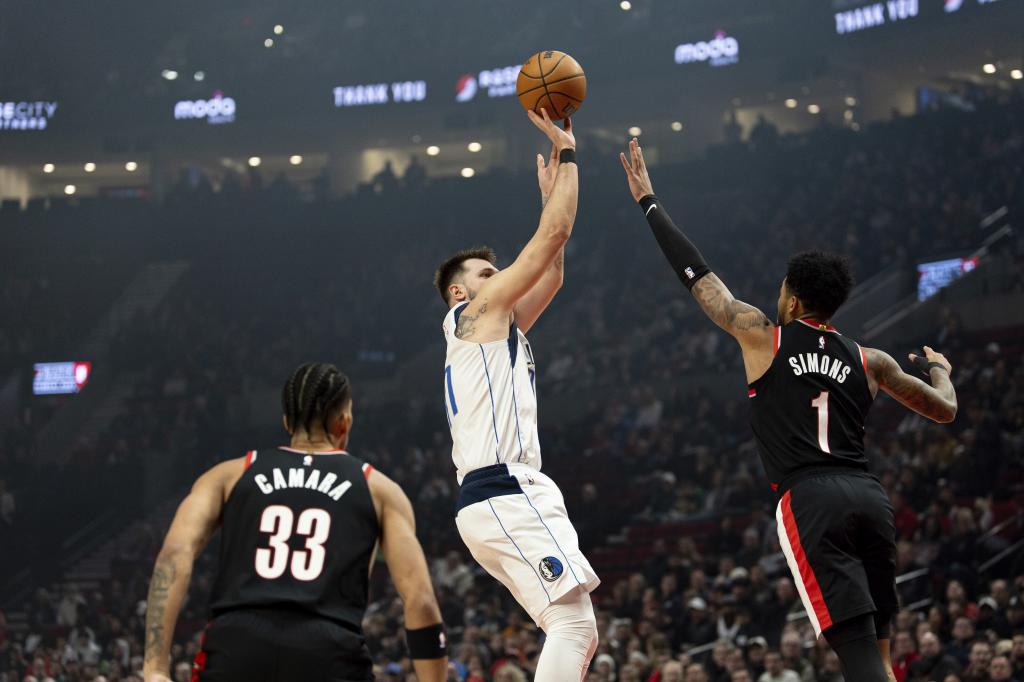 Dallas Mavericks guard Luka Doncic, center, goes up to shoot over Portland Trail Blazers guard Anfernee Simons, right, during the first half of an NBA basketball game Sunday, Dec. 1, 2024, in Portland, Ore. (AP Photo/Howard Lao)