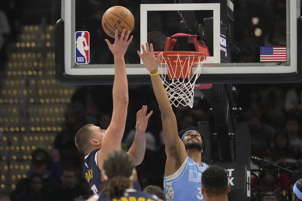 Denver Nuggets center Nikola Jokic, left, shoots over Cleveland Cavaliers center Jarrett Allen, right, in the first half of an NBA basketball game, Thursday, Dec. 5, 2024, in Cleveland. (AP Photo/Sue Ogrocki)