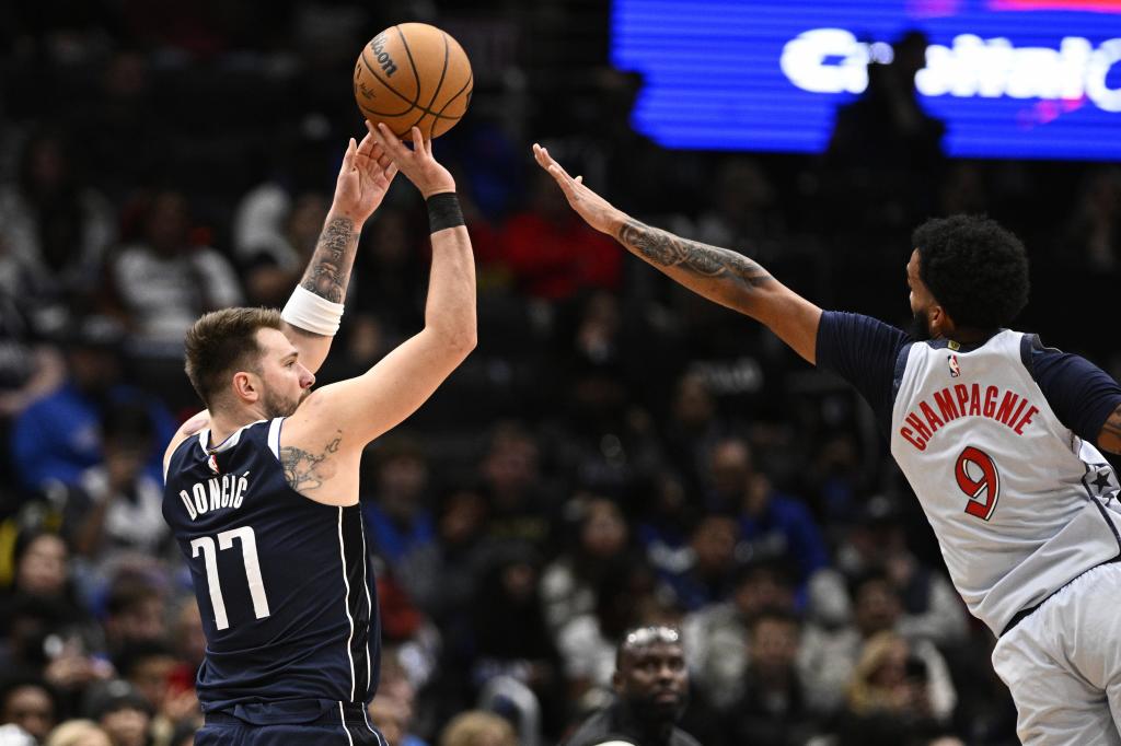 El escolta de los Mavericks de Dallas , Luka Doncic (77), busca disparar contra el alero de los Wizards de Washington, Justin Champagnie (9), durante la primera mitad de un partido de baloncesto de la NBA, el jueves 5 de diciembre de 2024, en Washington. (AP Foto/Nick Wass)