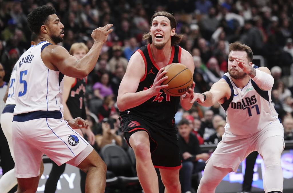 Toronto Raptors' Kelly Olynyk (41) drives between Dallas Mavericks' Quentin Grimes (5) and Luka Doncic (77) during first half NBA basketball action in Toronto on Saturday, December 7, 2024. (Nathan Denette/The Canadian Press via AP)