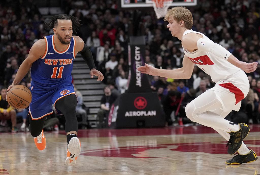 New York Knicks guard Jalen Brunson (11) drives past Toronto Raptors guard Gradey Dick (1) during the second half of an NBA basketball game against the New York Knicks, in Toronto, Monday, Dec. 9, 2024. (Nathan Denette/The Canadian Press via AP)