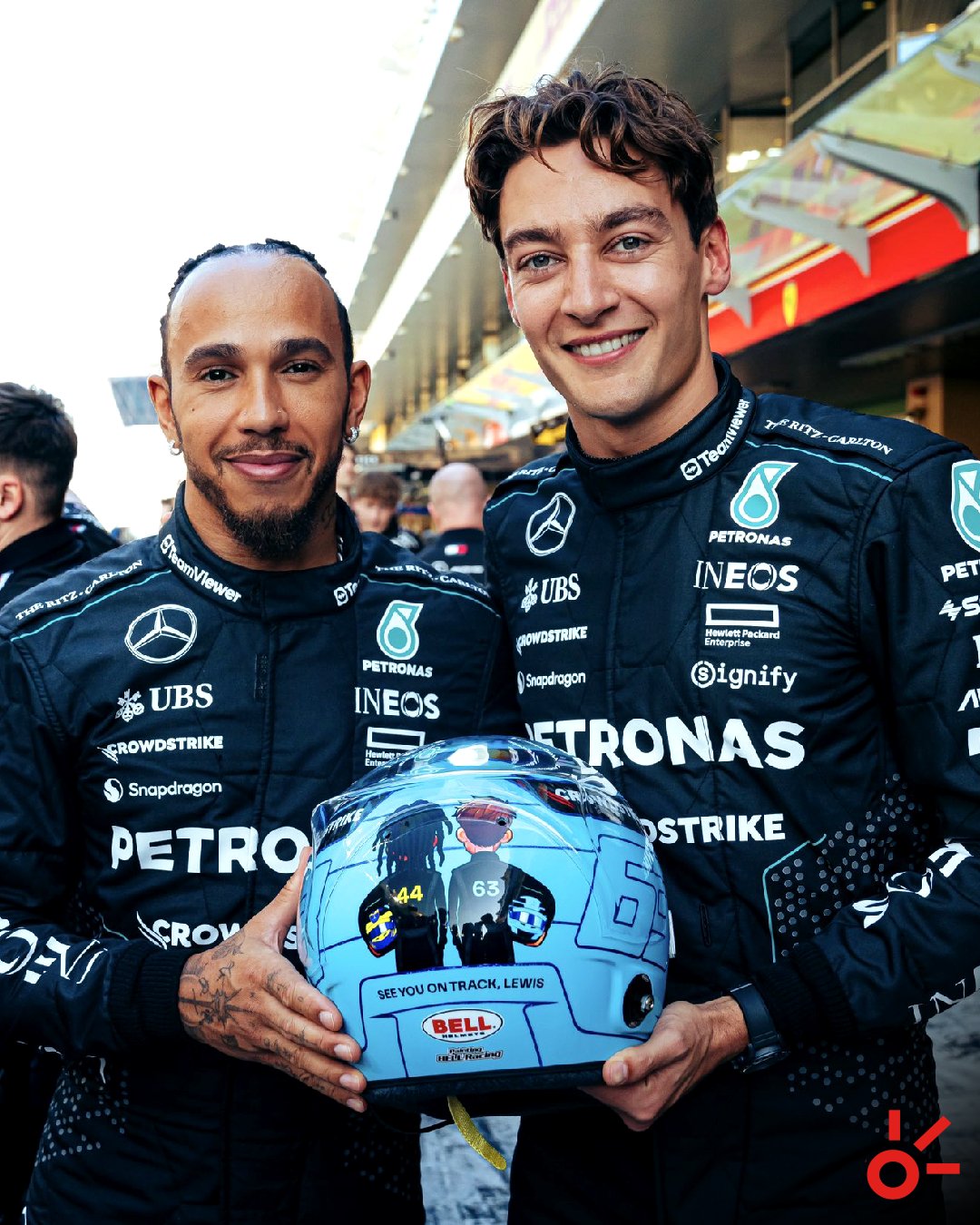 George Russell muestra un casco especial a Lewis Hamilton