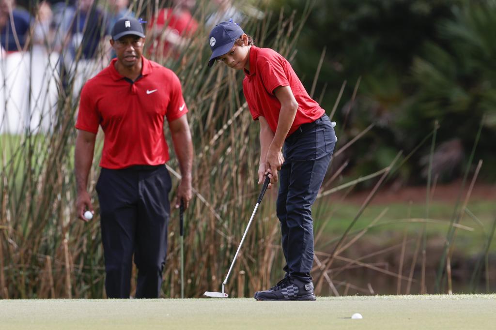 Charlie Woods mete un putt en el segundo green mientras es observado por el padre Tiger Woods