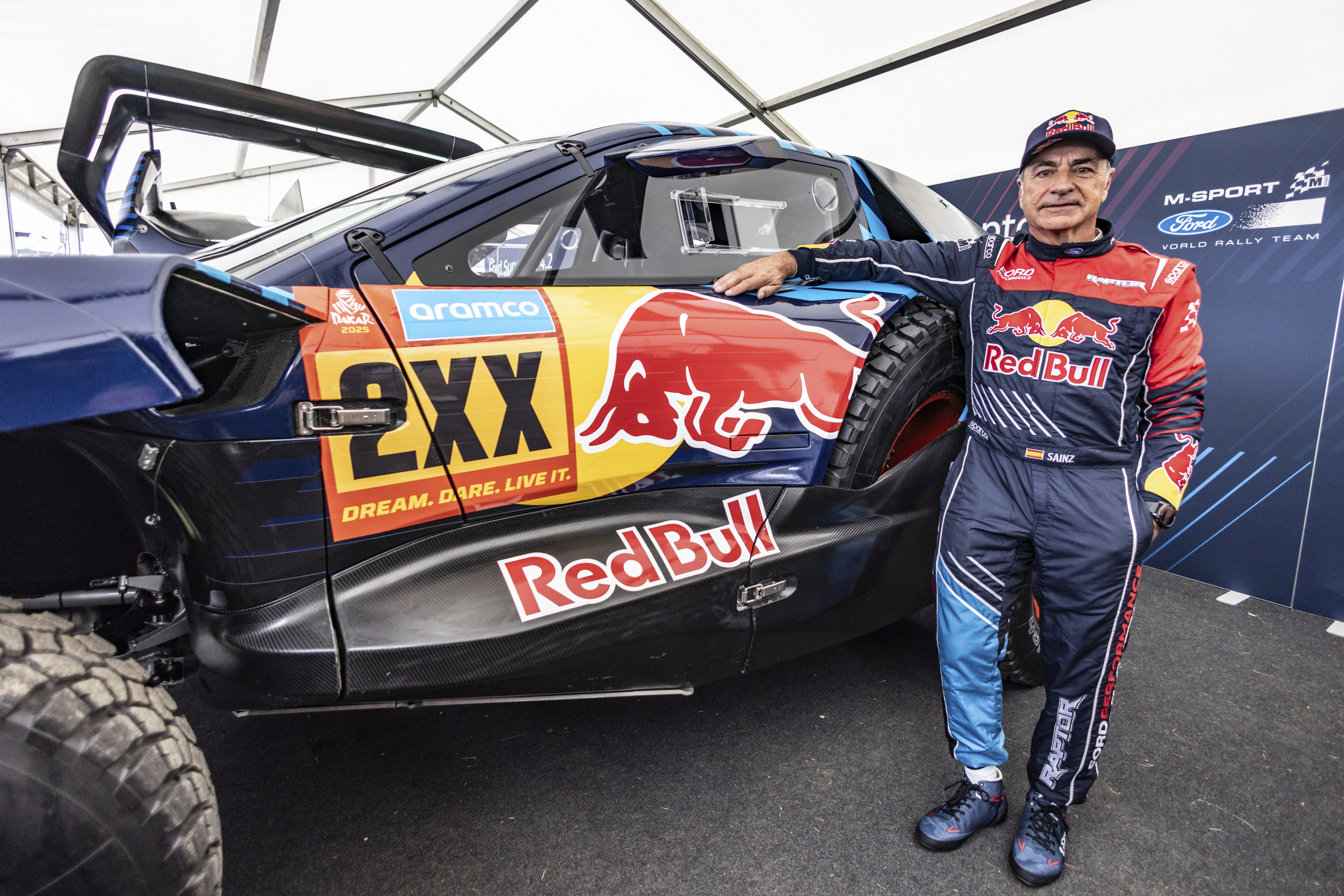 Carlos Sainz posa con el coche con el competirá en el Dakar 2025.