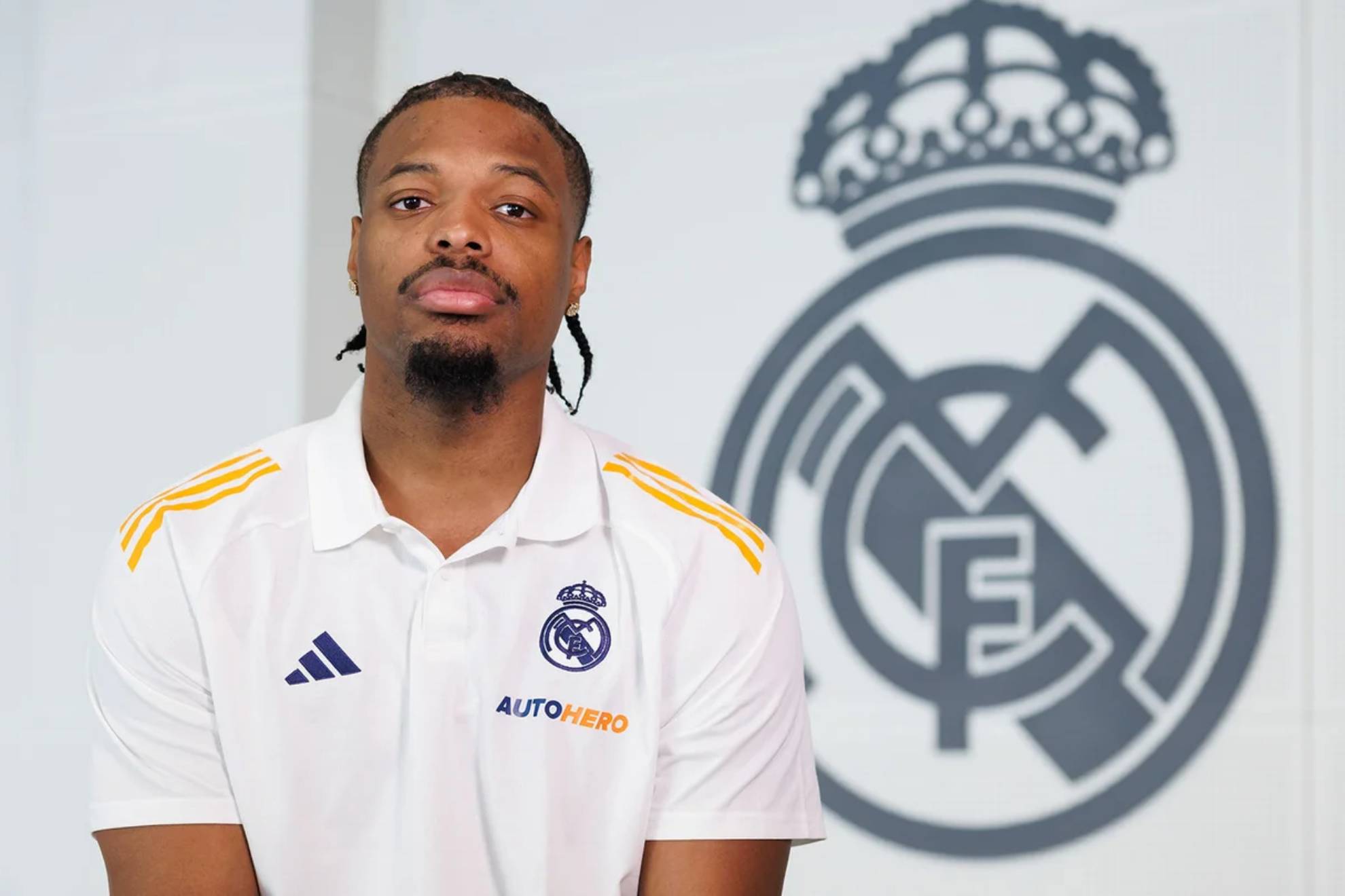 Dennis Smith Jr. poses in front of a Real Madrid shield.