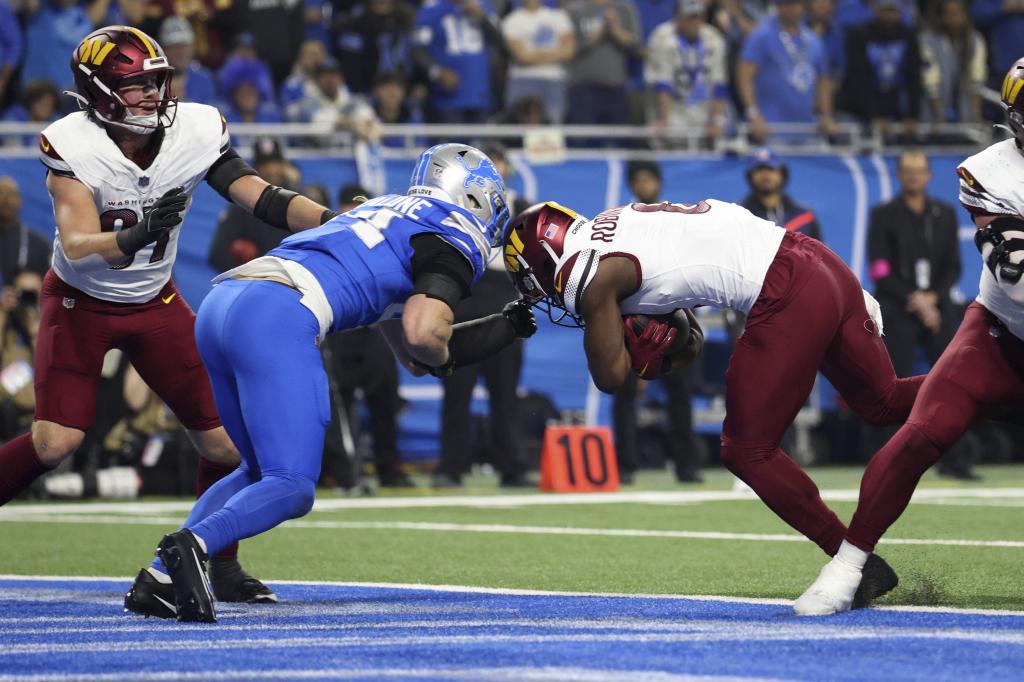 Detroit Lions wide receiver Allen Robinson (8) runs for a two-yard touchdown as Detroit Lions linebacker Alex Anzalone (34) defends during the first half of an NFL football divisional playoff game, Saturday, Jan. 18, 2025, in Detroit. (AP Photo/Mike Mulholland)