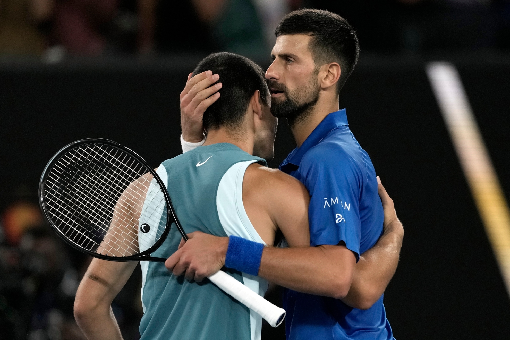 Alcaraz y Djokovic se abrazan en la red.