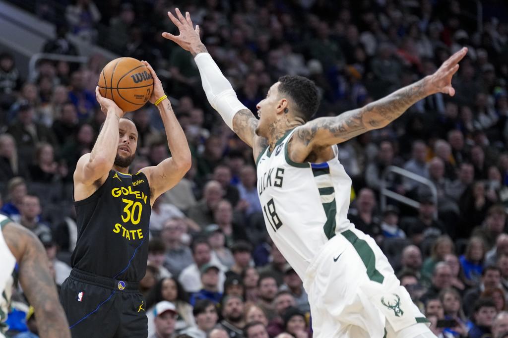 Curry lanza a canasta sin que Kuzma pueda puntear su tiro.