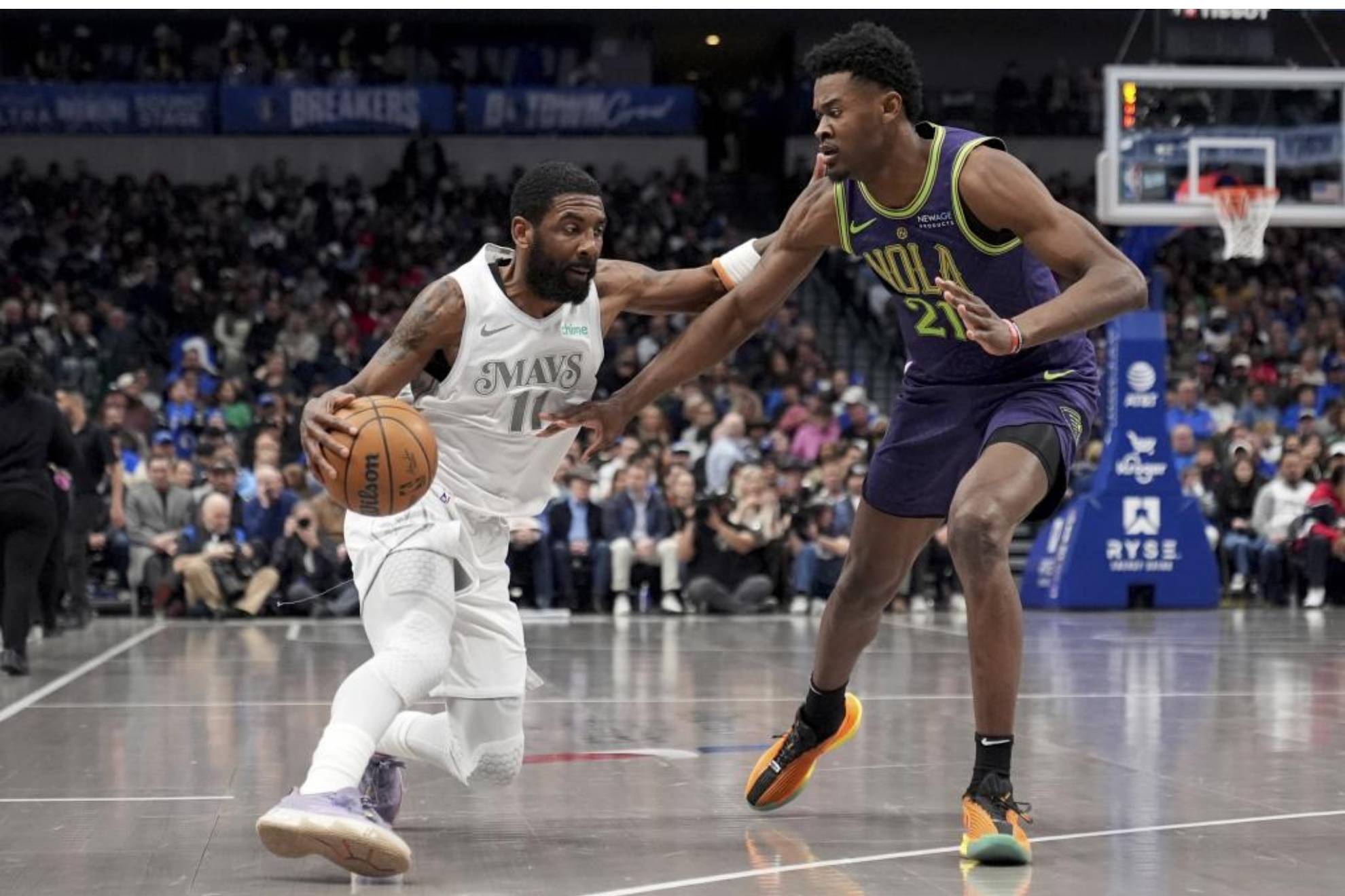 Kyrie Irving trata de superar la defensa de Yves Missi.