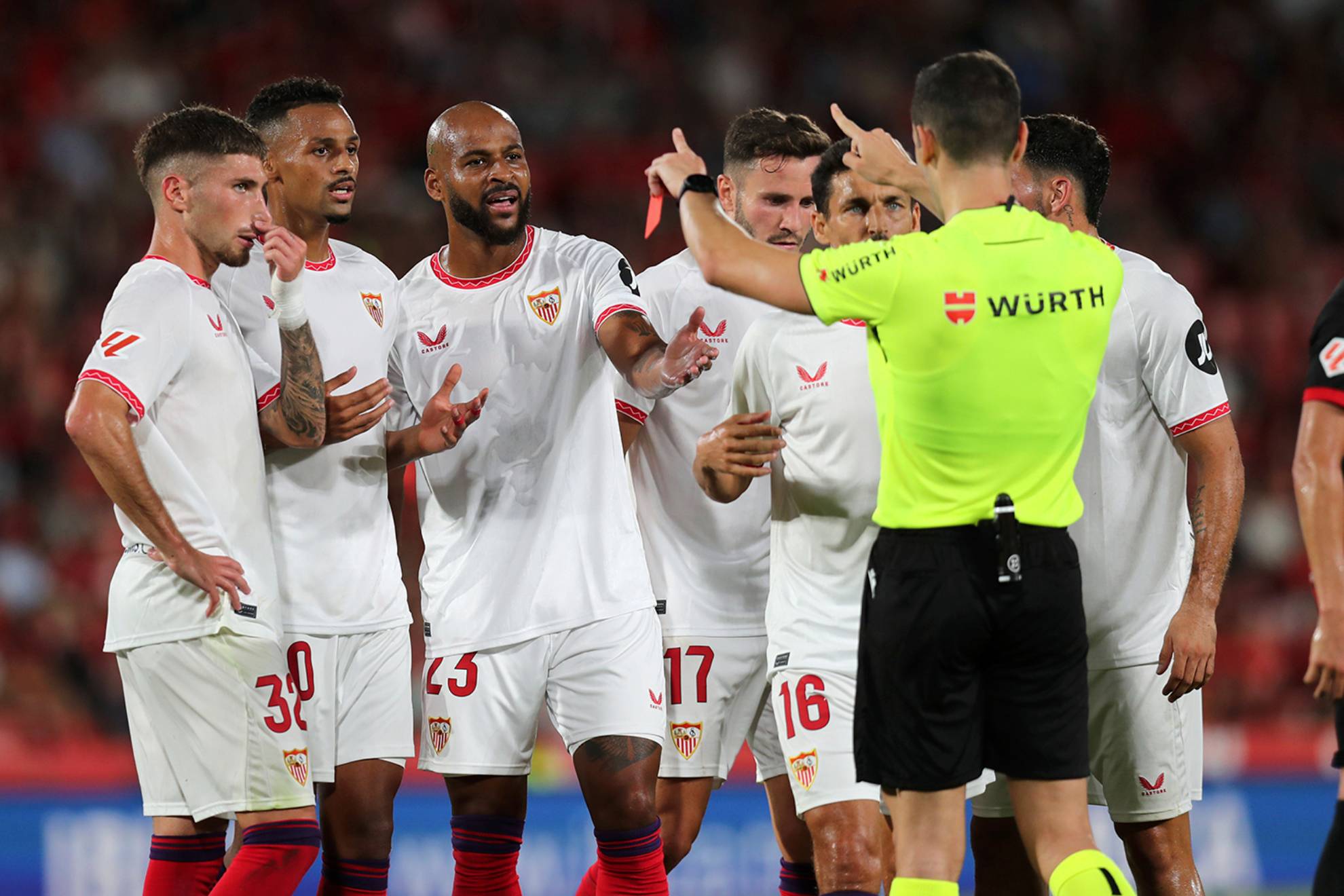 Los jugadores de Sevilla protestan al árbitro por la tarjeta roja de Saúl en Mallorca.