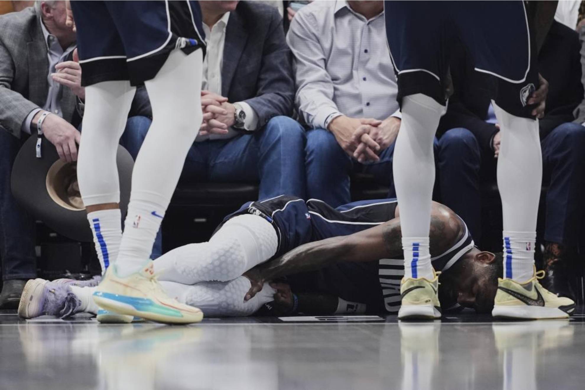 Kyrie Irving, tendido en el suelo, se echa la mano a la pierna izquierda lesionada.