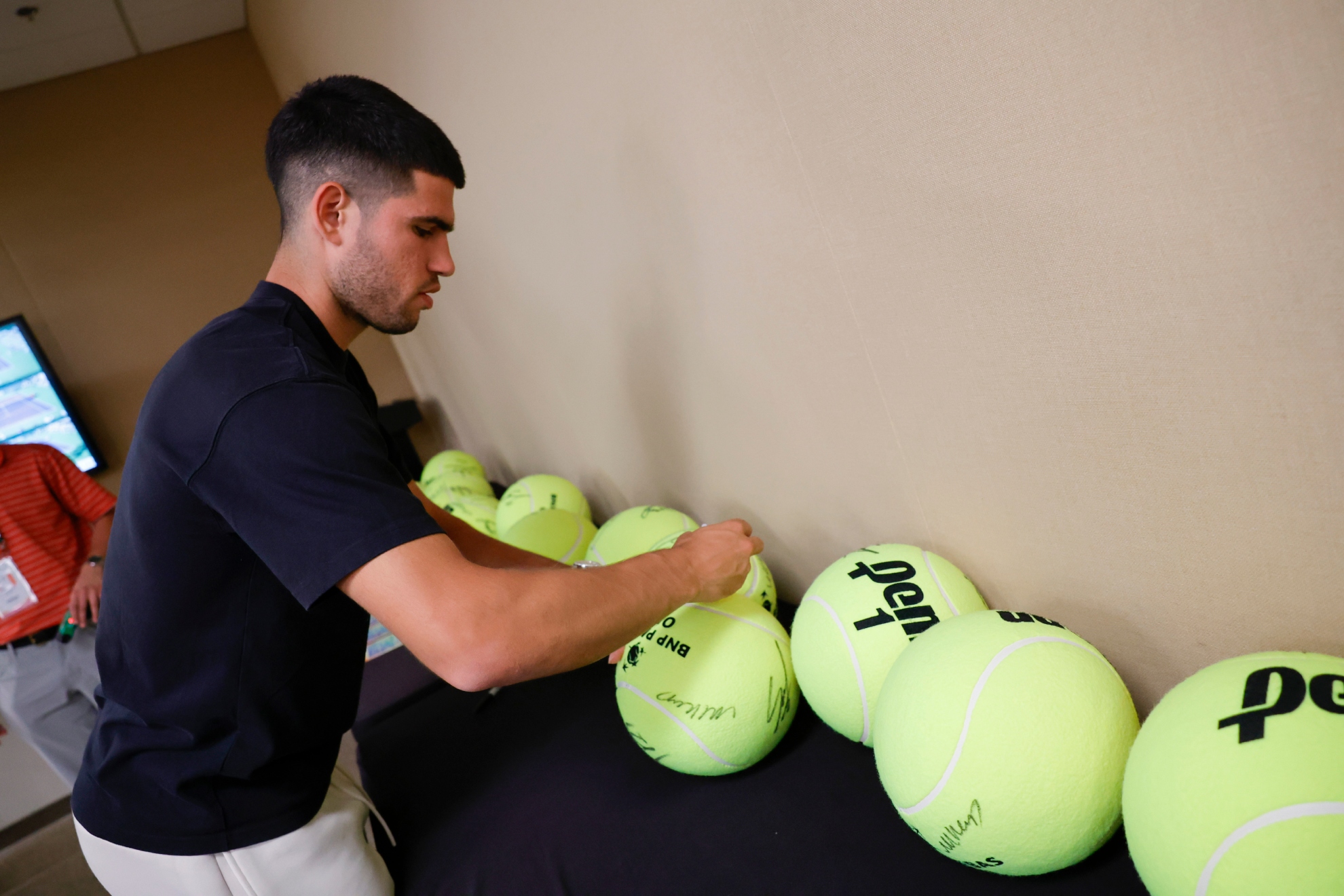 Alcaraz firma pelotas en el Tennis Garden.