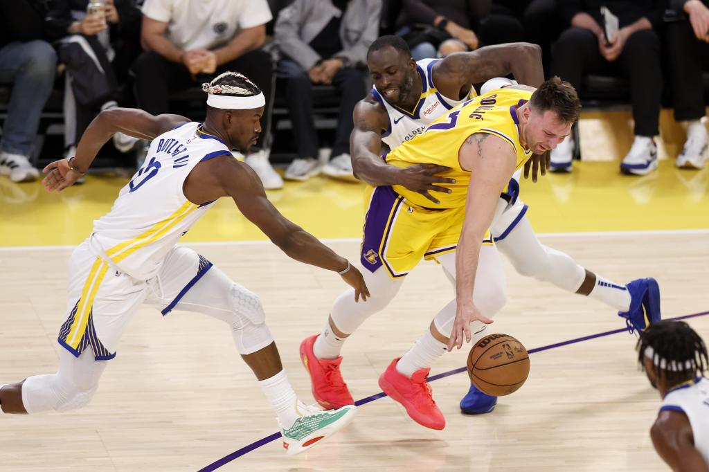 Luka Doncic intenta superar la presión de Jimmy Butler y Draymond Green.