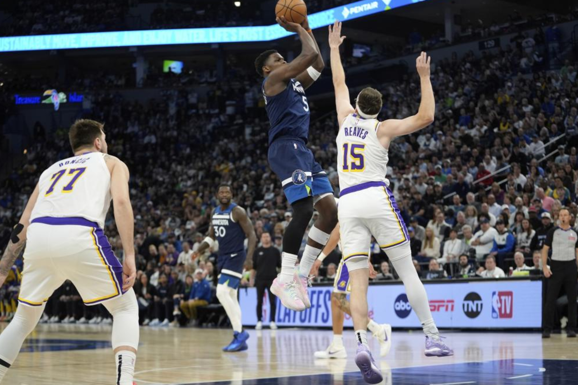 Anthony Edwards lanza sobre Austin Reaves con Doncic a un lado.
