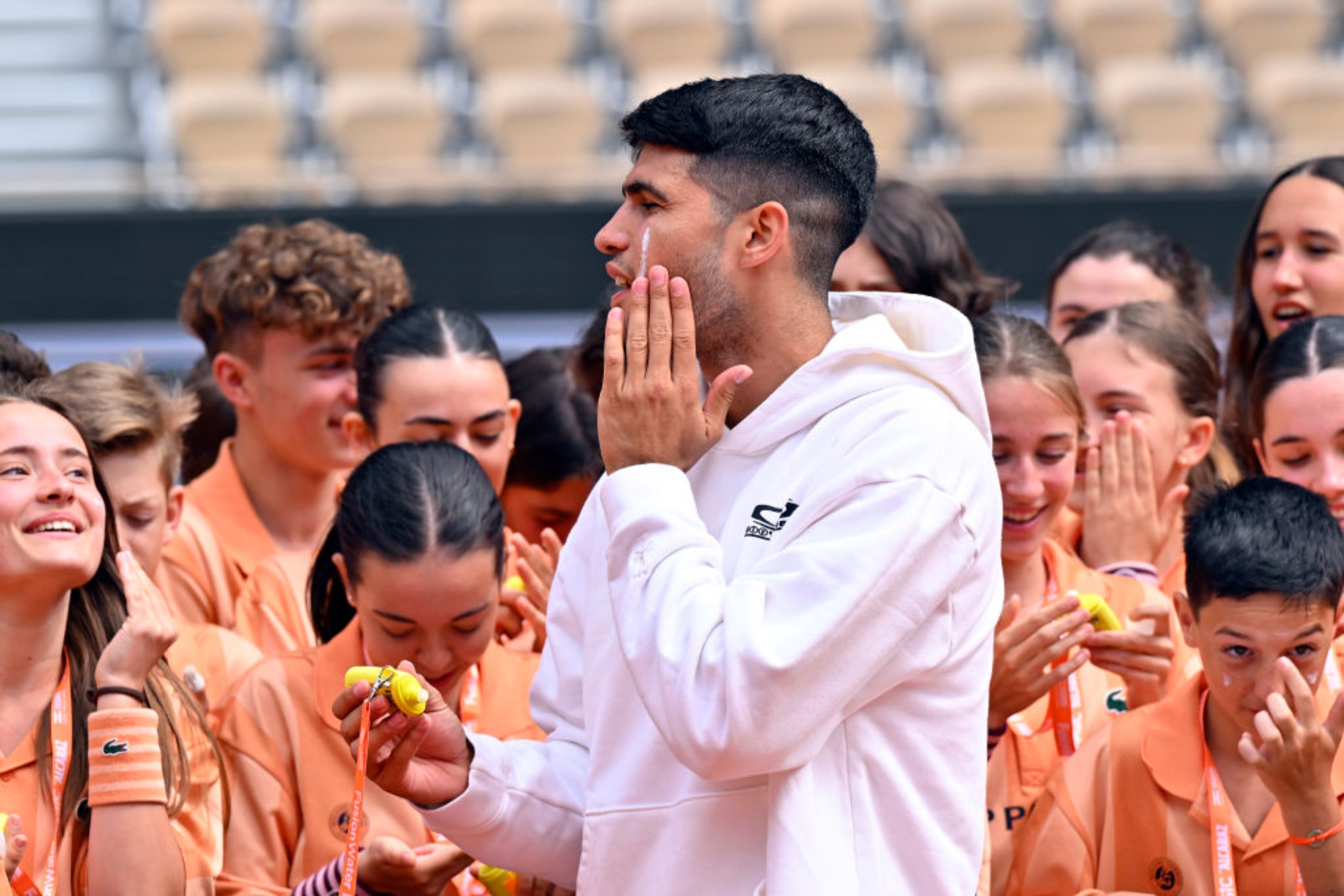 Alcaraz se pone crema en la cara para protegerse del sol.
